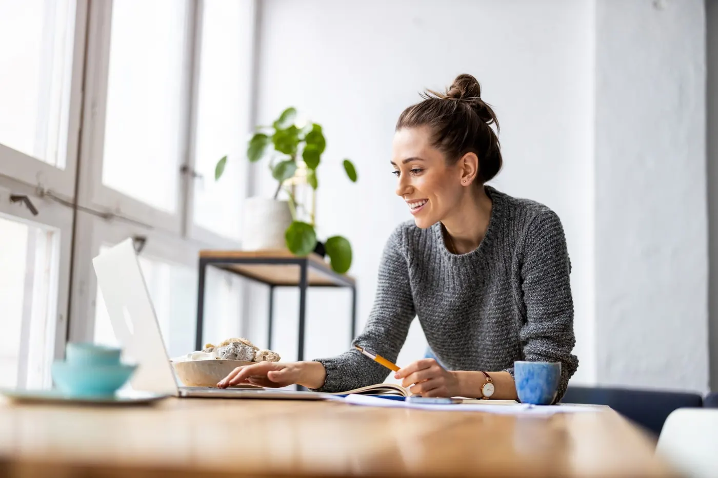 Eine Frau arbeitet am Laptop und skizziert auf Papier